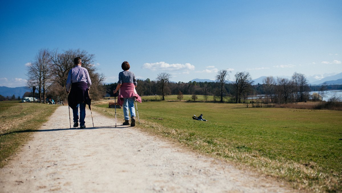 Zwei Senioren gehen mit Wanderstöcken in der Natur spazieren. (Symbolbild)