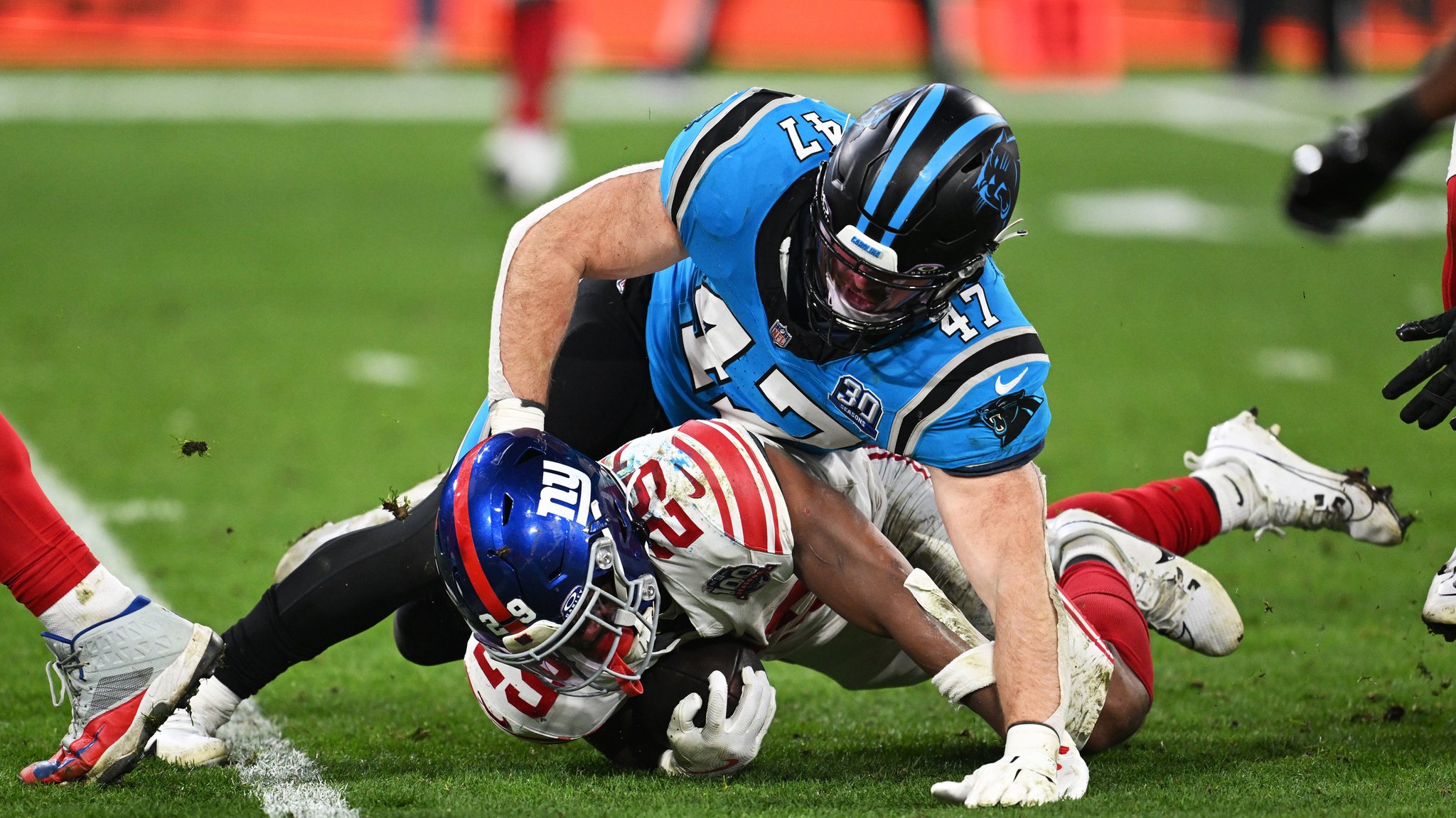 10.11.2024, Bayern, München: American Football: Profiliga NFL, Carolina Panthers - New York Giants, Hauptrunde, Hauptrunde-Partien, Spieltag 10, Allianz Arena, Giants Running Back Tyrone Tracy Jr (unten) wird von Panthers Linebacker Josey Jewell zu Boden gebracht. 