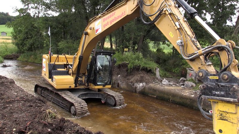 Ein Bagger reißt das Wehr an der Weiler Mühle bei Bidingen ab. Der Hühnerbach soll renaturiert werden. | Bild: BR/Florian Regensburger Ein Bagger reißt das Wehr an der Weiler Mühle bei Bidingen ab. Der Hühnerbach soll renaturiert werden.