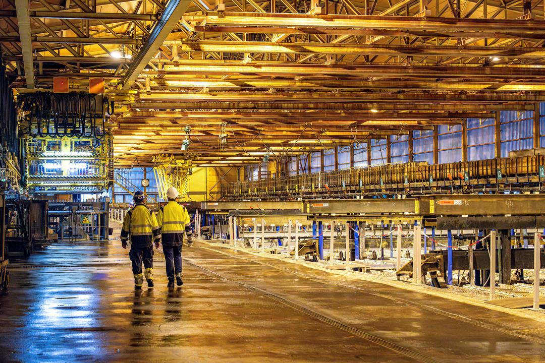 Arbeiter laufen durch eine Zinkhütte. 