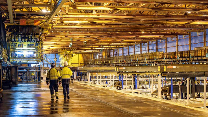 Arbeiter laufen durch eine Zinkhütte. | Bild: dpa-Bildfunk/Sina Schuldt Arbeiter laufen durch eine Zinkhütte.