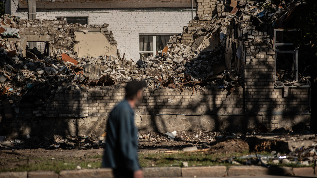 Ein Mann geht an zerstörten Gebäuden entlang.