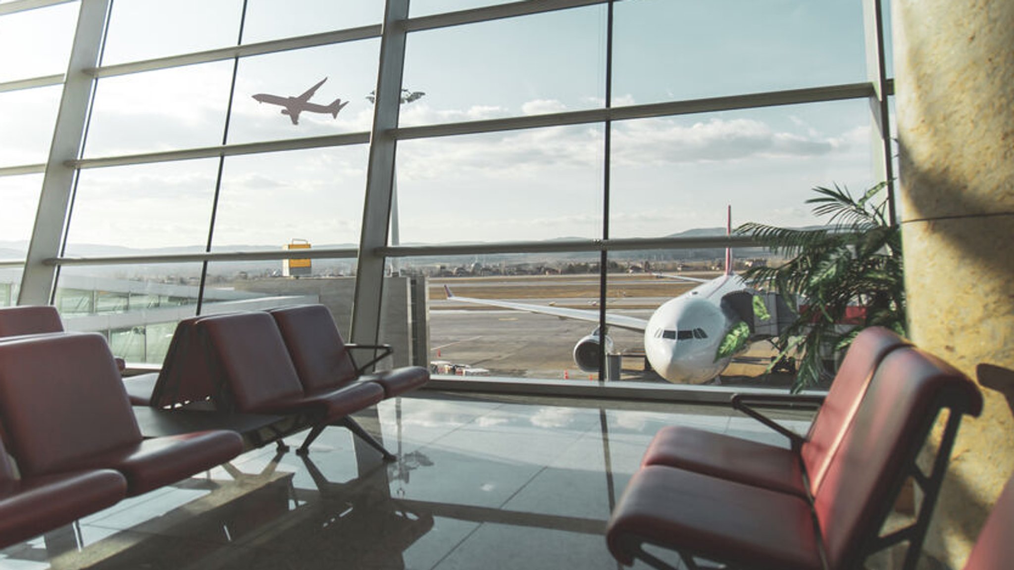 Ein leerer Wartebereich im Terminal eines Flughafens mit Blick auf des Rollfeld.