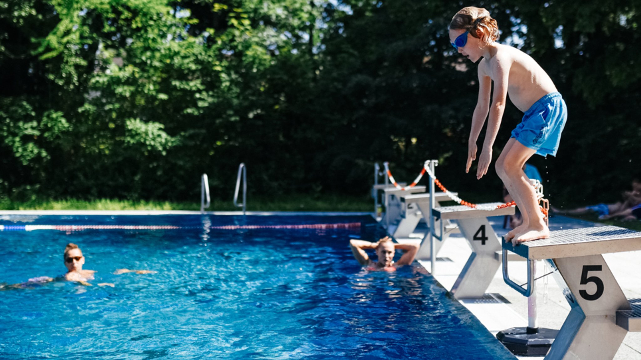 Ein Kind auf einem Startblock im Freibad