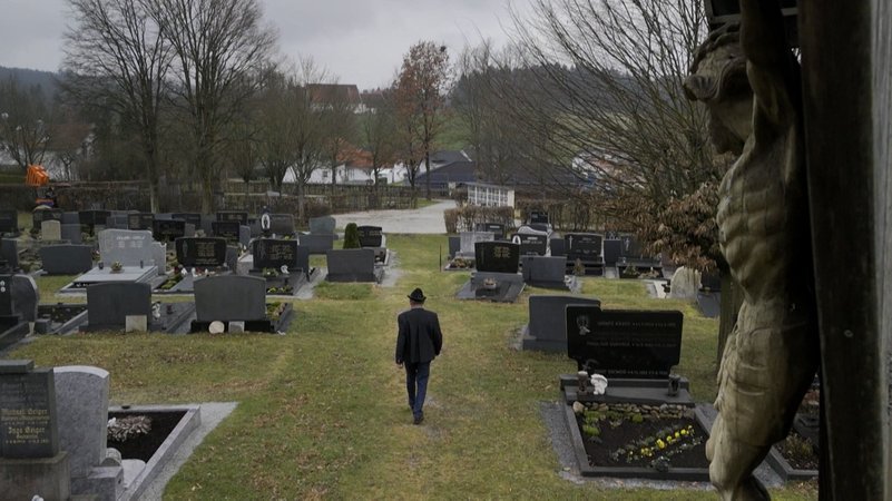 Ein Mann geht einen Friedhofsweg entlang.