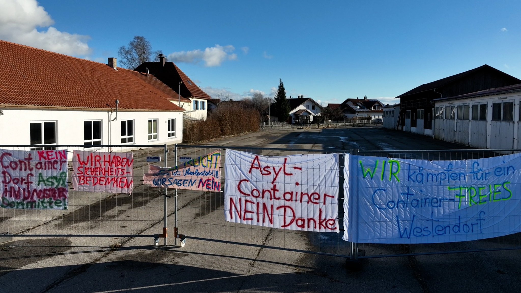 Am Zaun vor dem leerstehenden Bauhof in Westendorf sind Transparente gegen eine Containersiedlung angebracht.