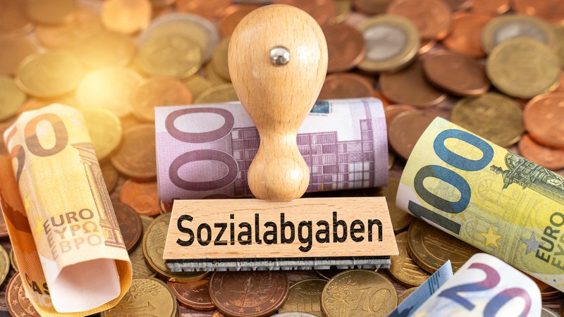 Ein Stempel mit dem Begriff Sozialabgaben liegt auf Euro-Scheinen | Bild: picture alliance / CHROMORANGE | Michael Bihlmayer Ein Stempel mit dem Begriff Sozialabgaben liegt auf Euro-Scheinen