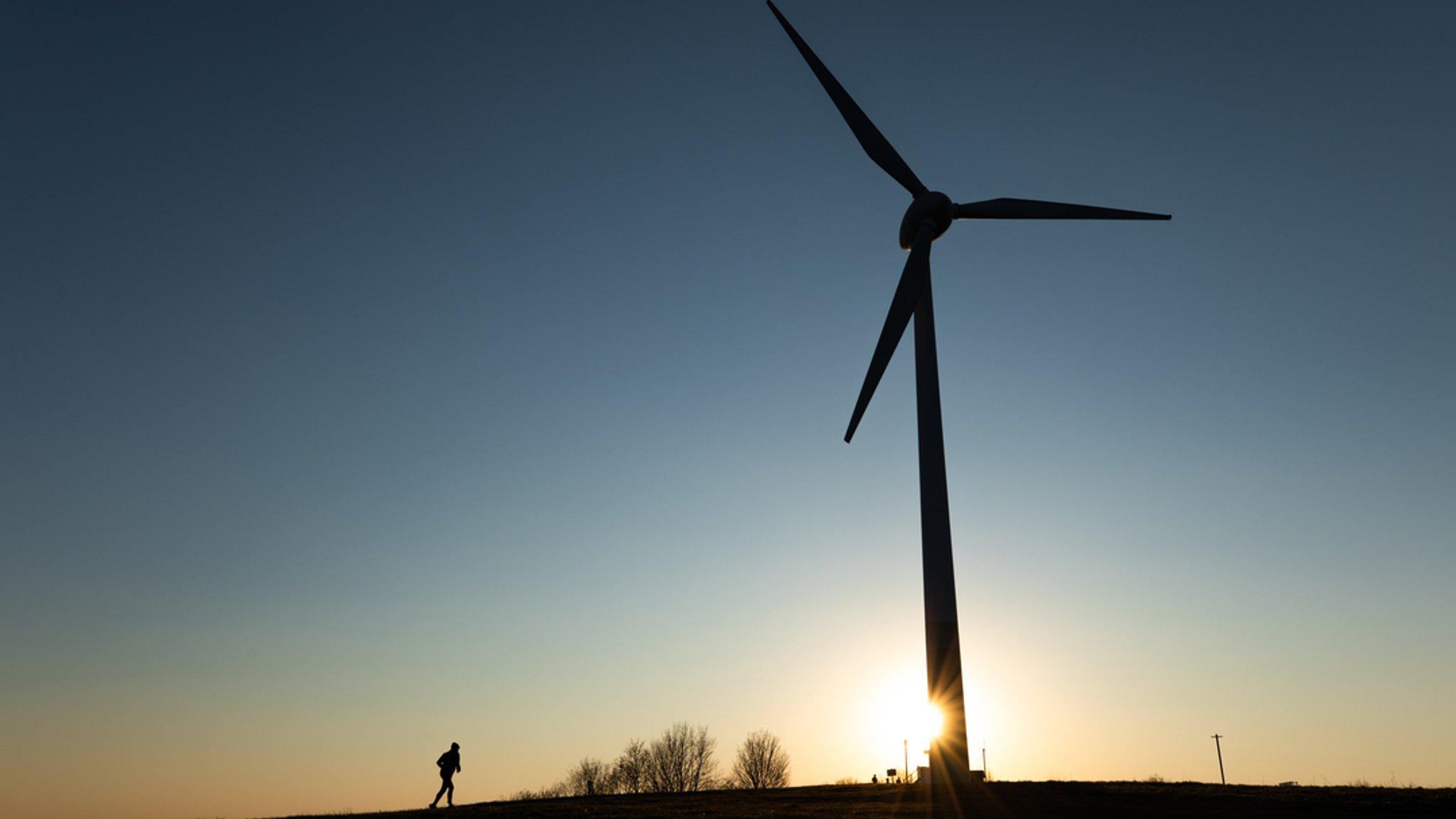 Die Silhouette einer Windkraftanlage bei Sonnenuntergang.