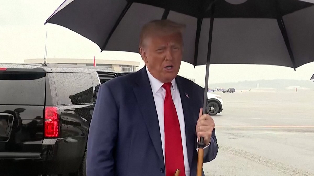 Ex-US-Präsident Trump hält einen Regenschirm