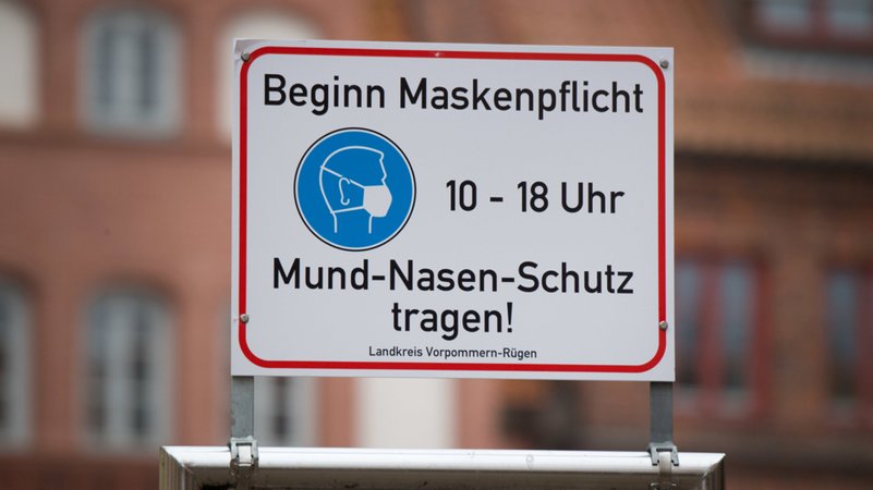 "Beginn Maskenpflicht" steht auf einem Schild in der Altstadt von Stralsund. 