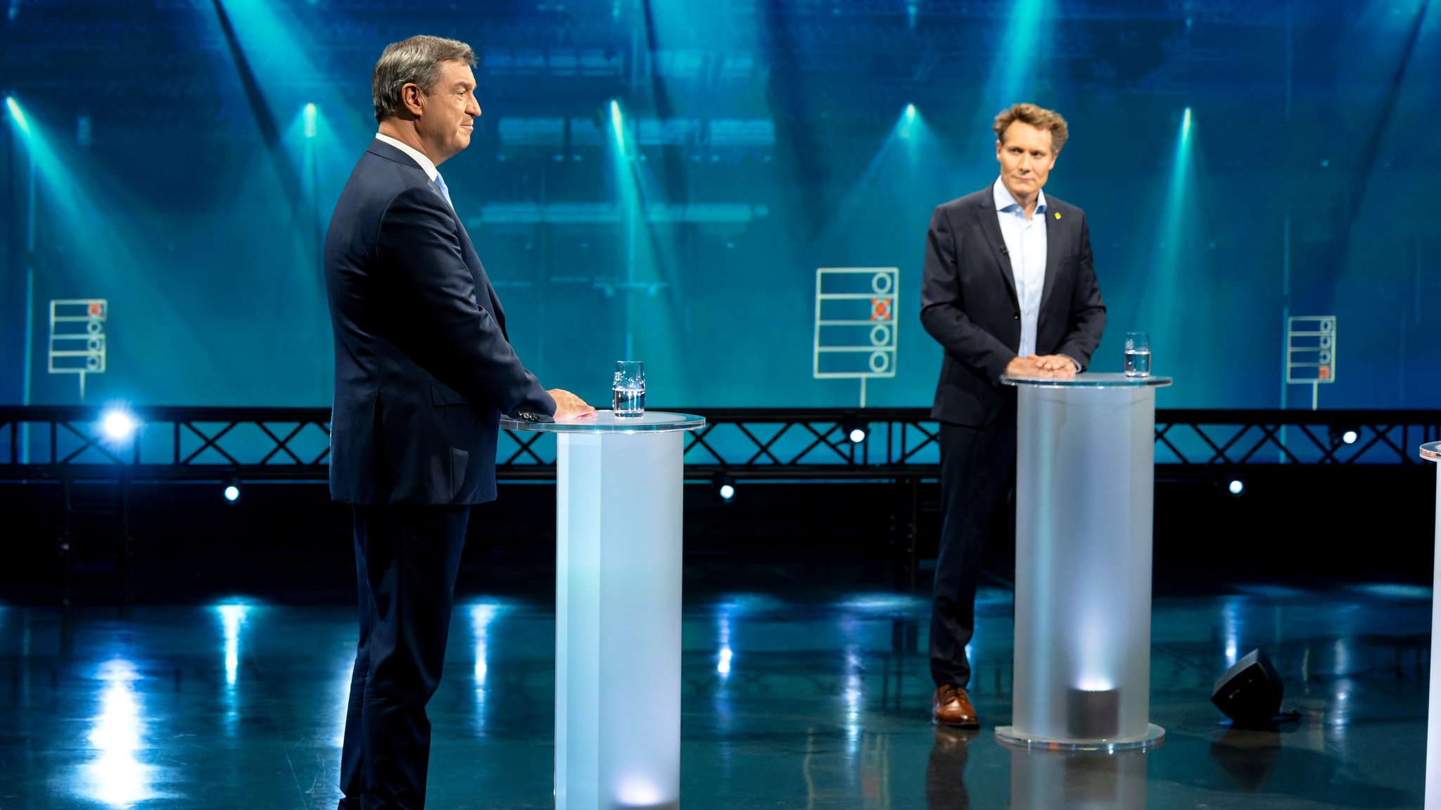 Markus Söder (CSU) und Ludwig Hartmann (B'90/Grüne) stehen sich in einem Fernsehstudio gegenüber