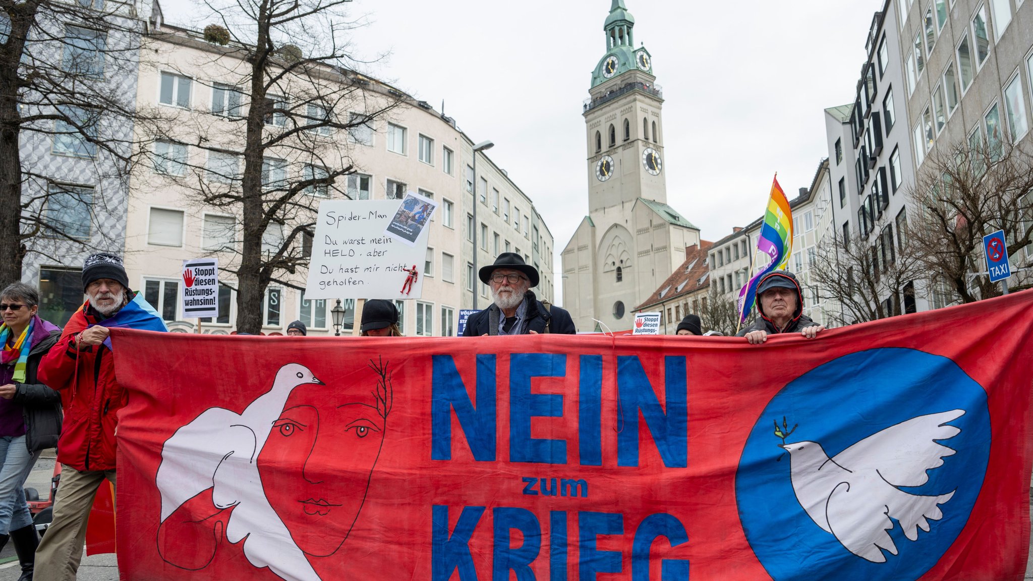 Menschen ziehen beim Ostermarsch hinter einem Transparent mit Friedenstauben und dem Aufdruck "Nein zum Krieg" durch die Münchner Altstadt.
