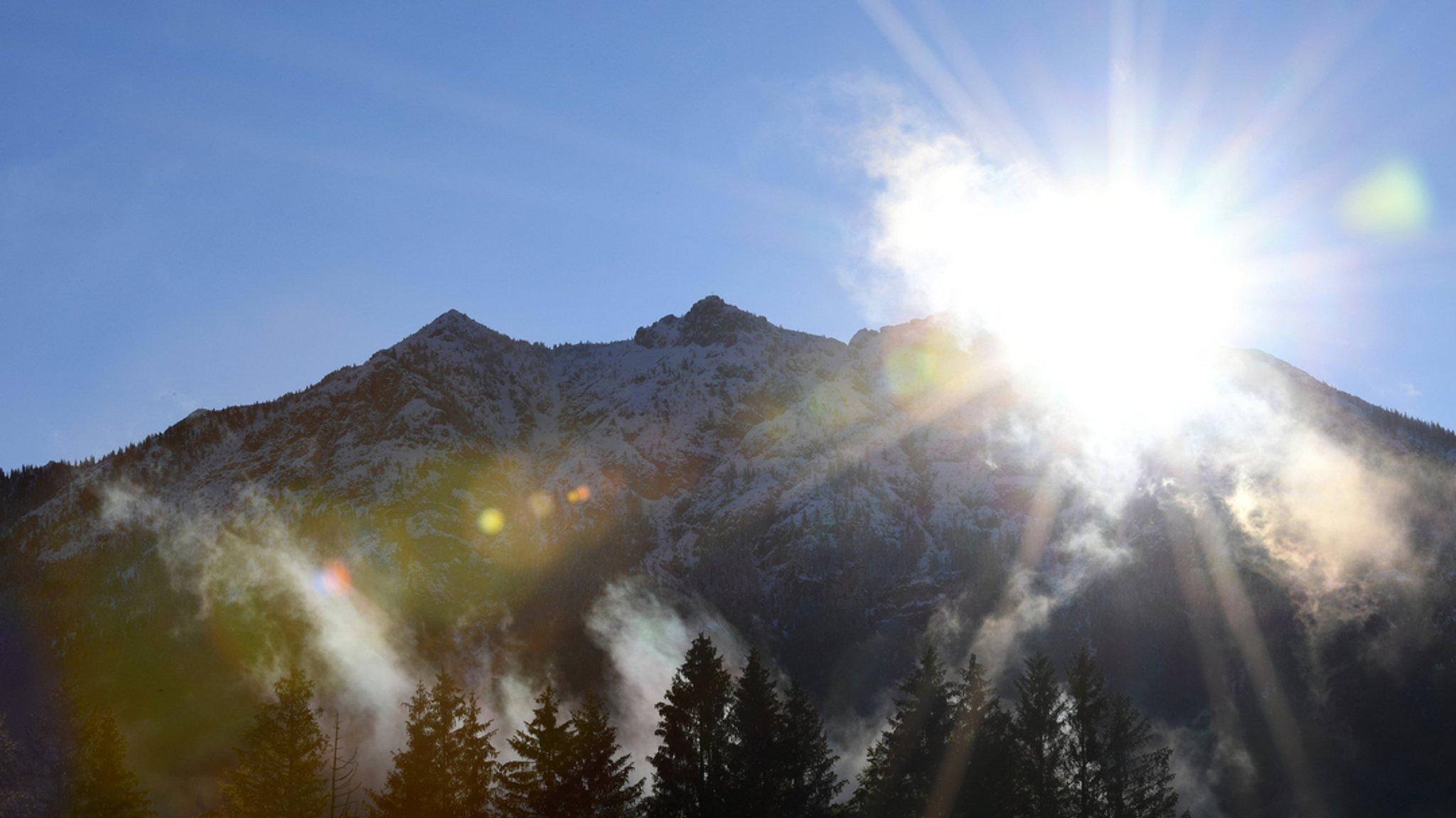 Morgennebel steigt über den Wiesen vor den Gipfeln des schneebedeckten Karwendelgebirges auf (Archivbild).