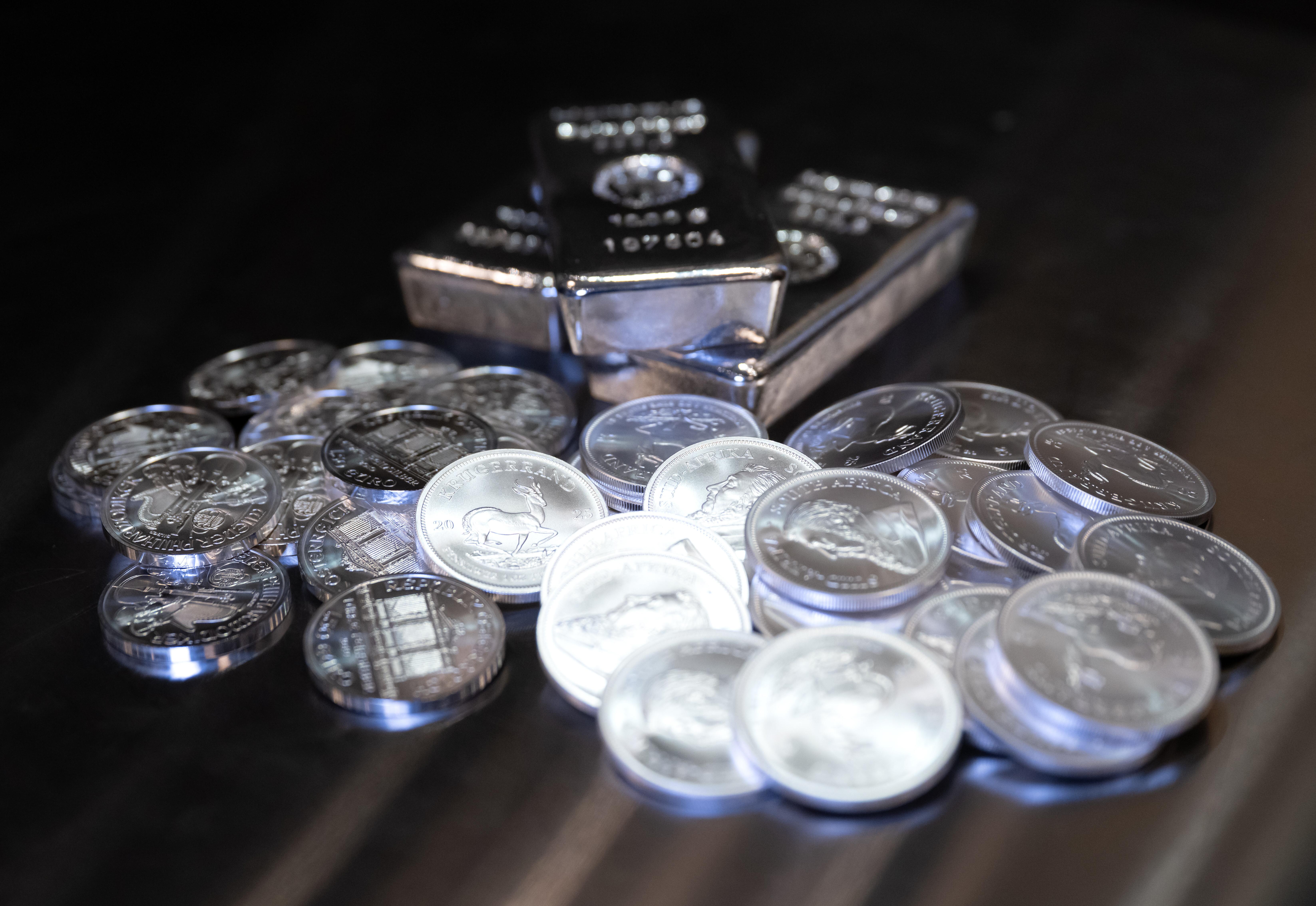 Einige Silbermünzen und Silberbarren liegen auf einem Stapel