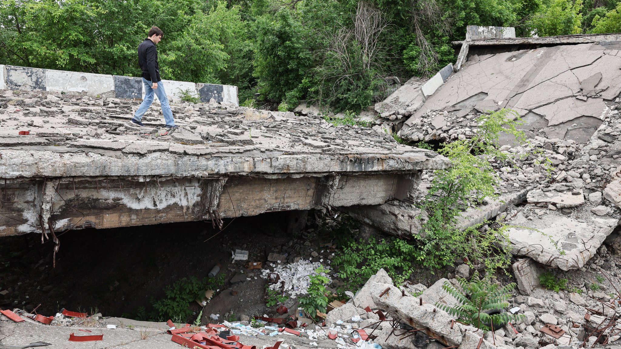 Junger Mann schreitet über Trümmer einer Betonbrücke