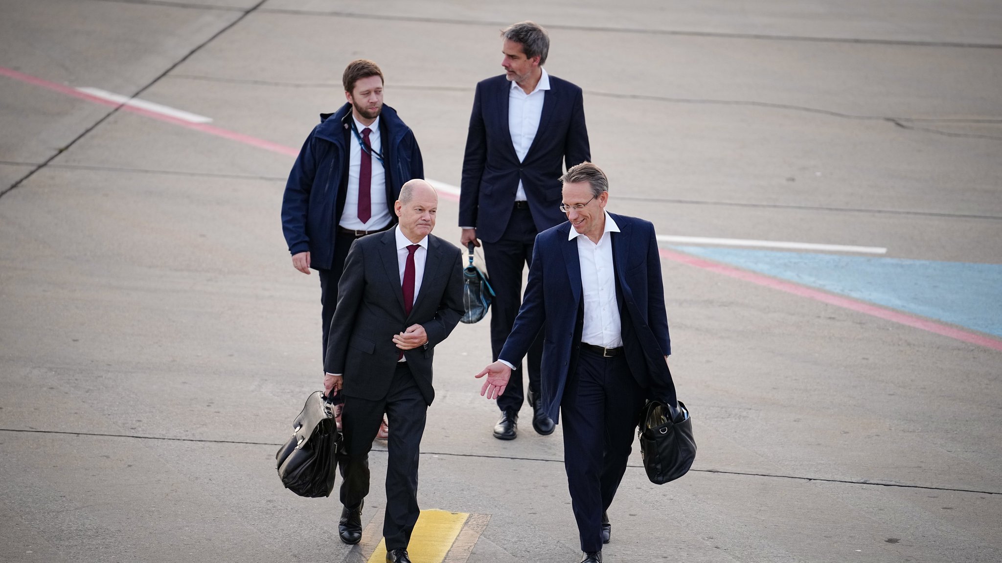 Bundeskanzler Olaf Scholz (SPD, vorn, l) kommt mit Jörg Kukies (r), wirtschaftspolitischer Berater des Kanzlers, und Steffen Hebestreit (hinten, r), Sprecher der Bundesregierung, für den Flug mit dem Airbus A340 der Luftwaffe zum Antrittsbesuch in China am militärischen Teil des Flughafens BER Berlin-Brandenburg an.