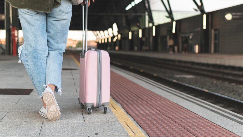 Symbolbild: Frau mit rosa Koffer läuft einen Bahnsteig entlang | Bild: picture alliance / Westend61 | Josu Acosta Symbolbild: Frau mit rosa Koffer läuft einen Bahnsteig entlang