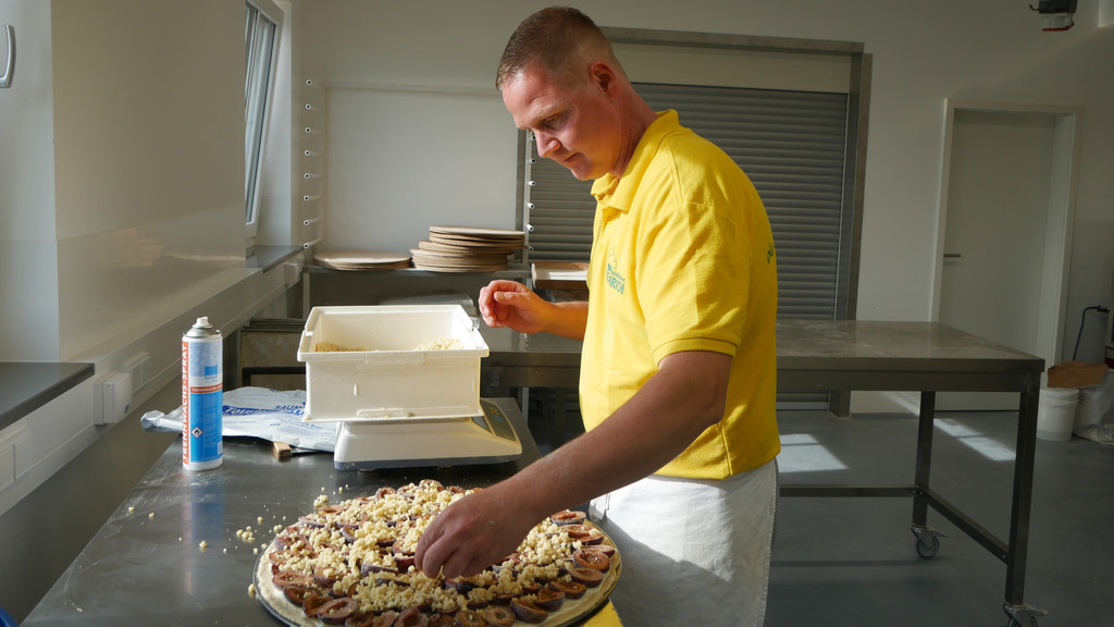 Bäckermeister und Konditor Sebastian Heinrich belegt seinen Streusel-Blooz mit Zwetschgen.
