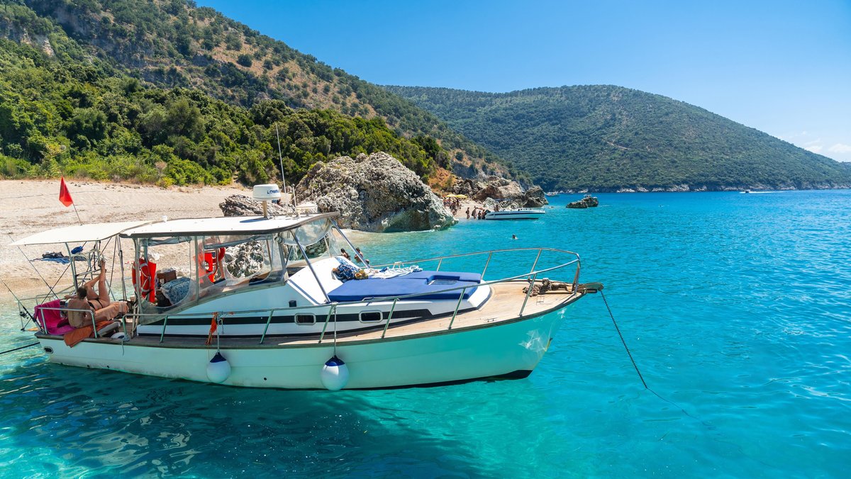 Boot im kristallklaren Wasser des paradiesischen Strandes von Kroreza oder Krorez vom Boot aus an der albanischen Riviera im albanischen Sarande