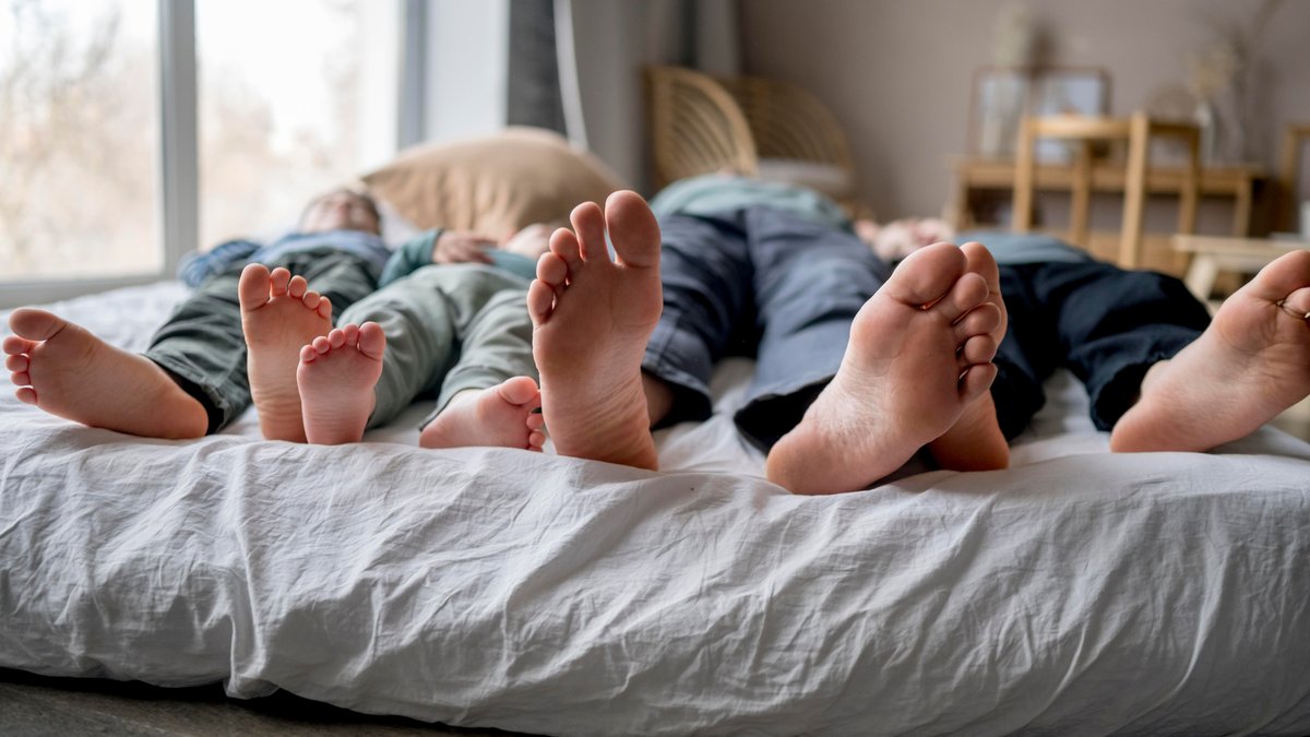 Viele Füße einer Familie in einem Bett. 
