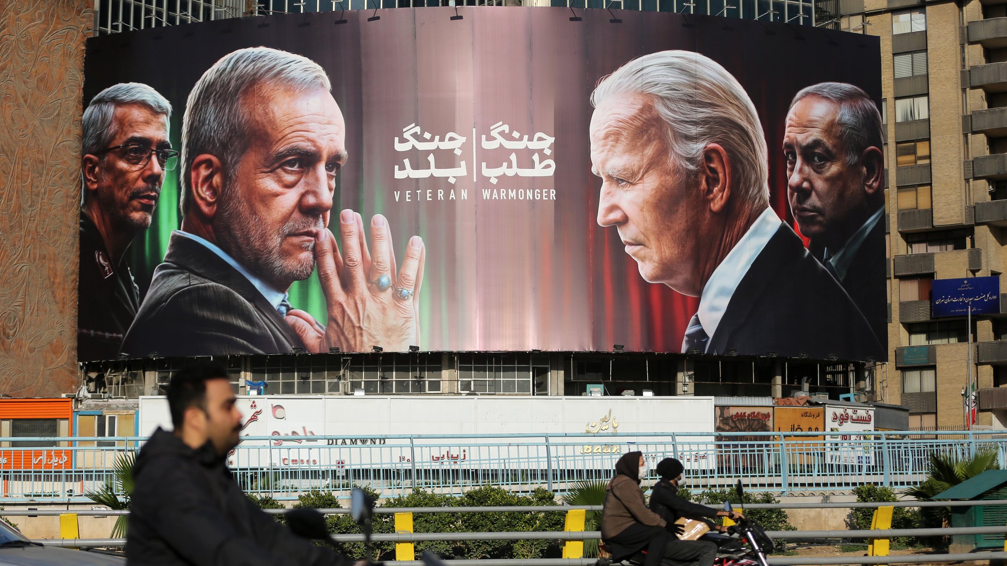 Banner in Teheran mit Präsident Peseschkian und US-Präsident Biden im Vordergrund. Hinter Biden ist Israels Premier Netanjahu zu sehen. 