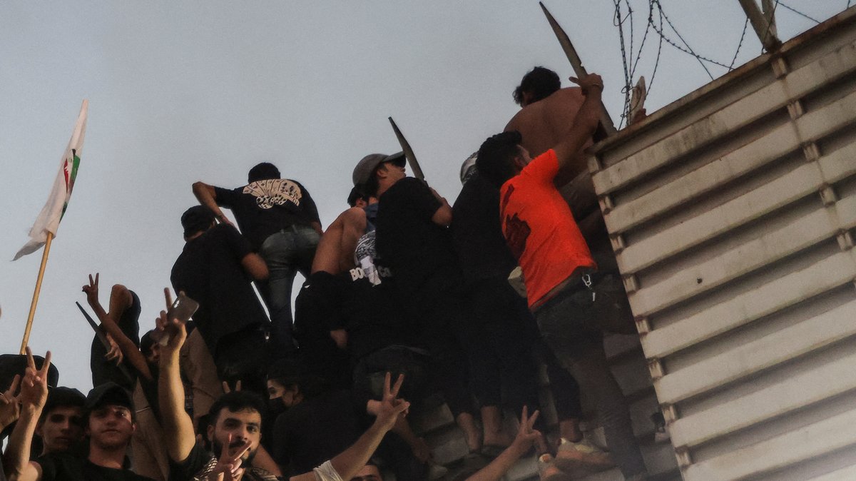 Protestierende klettern auf einen Zaun nahe der schwedischen Botschaft in Bagdad.