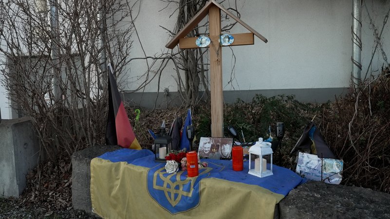 Neun Monate nach der Tat erinnert eine Gedenkstätte am Tatort nahe eines Einkaufszentrums in der Ortsmitte von Murnau an die Bluttat. | Bild: BR Neun Monate nach der Tat erinnert eine Gedenkstätte am Tatort nahe eines Einkaufszentrums in der Ortsmitte von Murnau an die Bluttat.