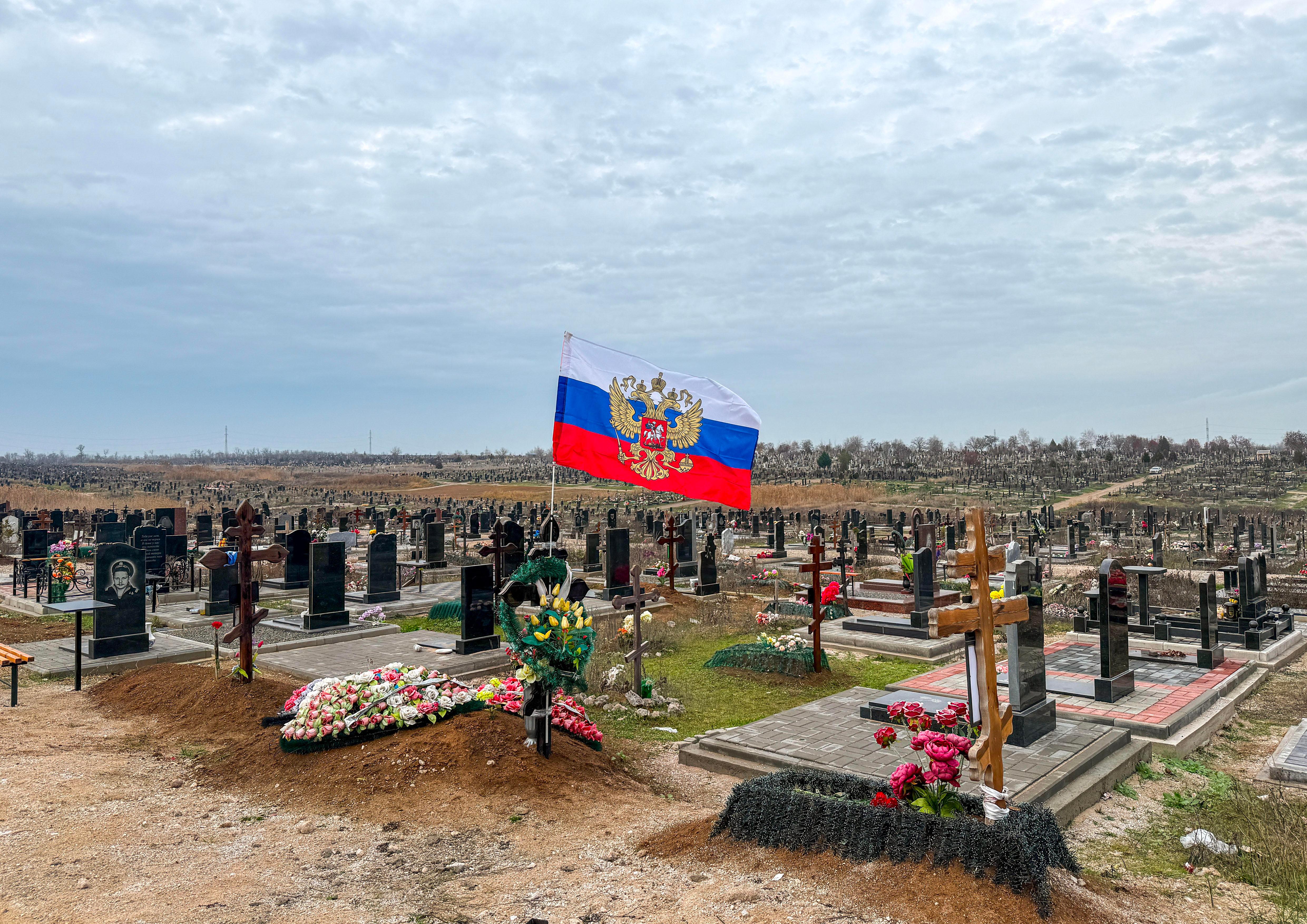 Eine russische Flagge flattert über einem Grab