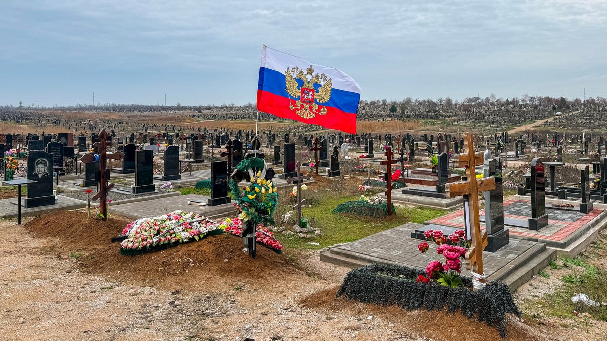 Eine russische Flagge flattert über einem Grab