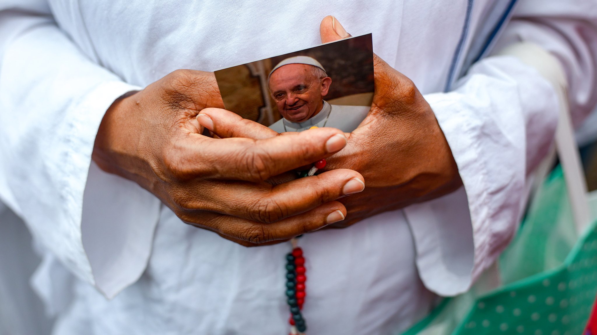 Ein Mann hält ein Bild des Papstes in den Händen.