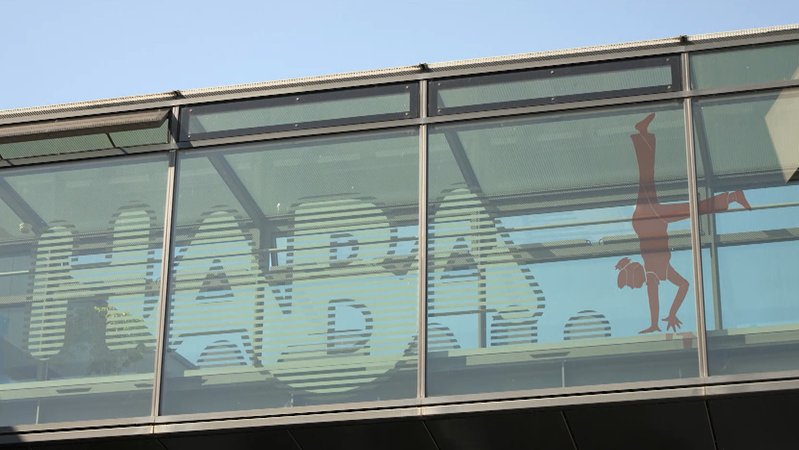 Auf einem verglasten Übergang zwischen zwei Gebäuden ist der Schriftzug "Haba" zu lesen. 