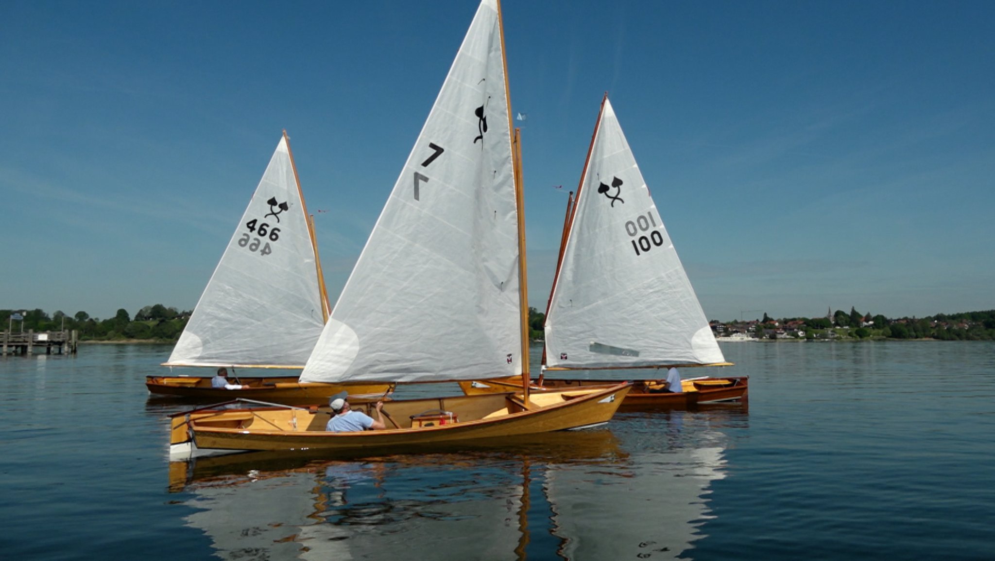 Drei Chiemseeplätten mit jeweils einem Segler an Bord auf dem Chiemsee