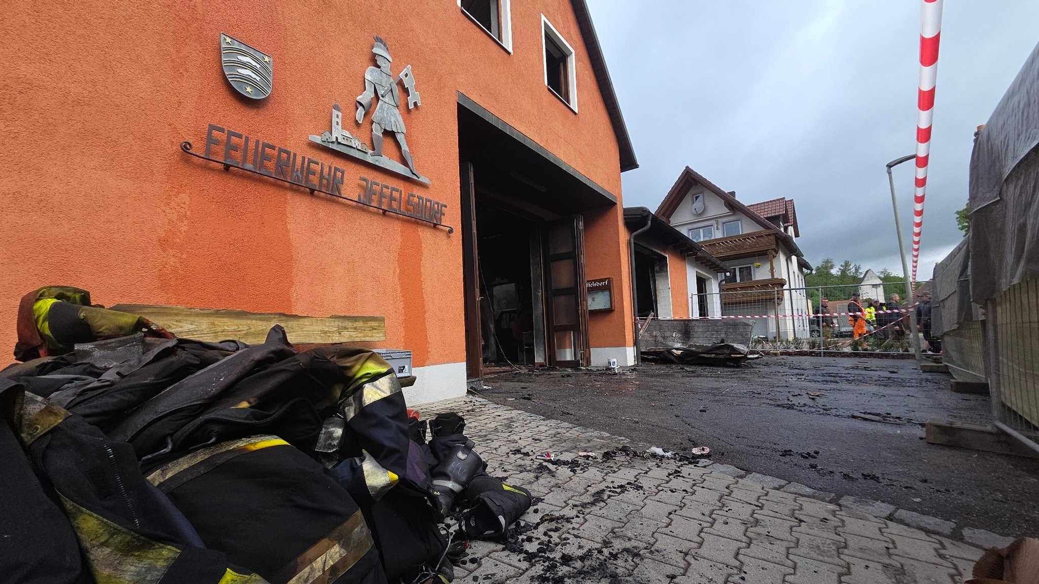 Das ausgebrannte Feuerwehrgerätehaus Iffelsdorf, davor verrußte Kleidung