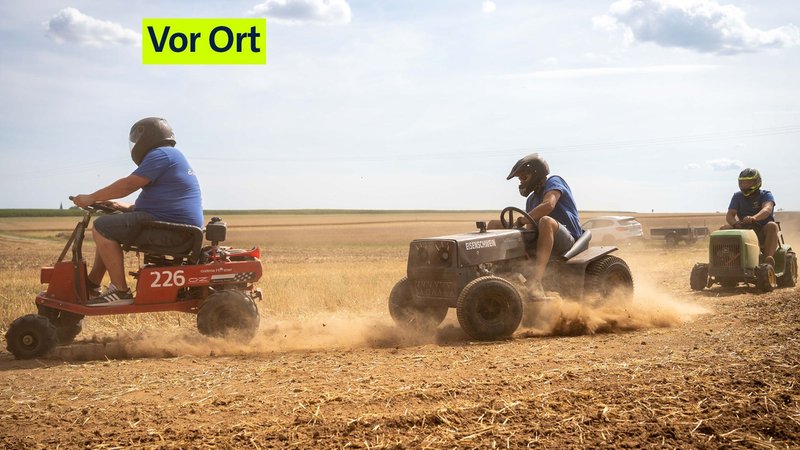 Ein Aufsitz-Rasenmäher fährt hinter einem anderen her, der Boden staubt. Die Fahrer tragen Helme. | Bild: BR24/Henry Lai Ein Aufsitz-Rasenmäher fährt hinter einem anderen her, der Boden staubt. Die Fahrer tragen Helme.