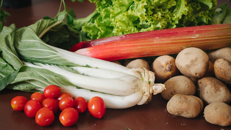 Frisches Gemüse, Salat und Kartoffeln auf einem Tisch.