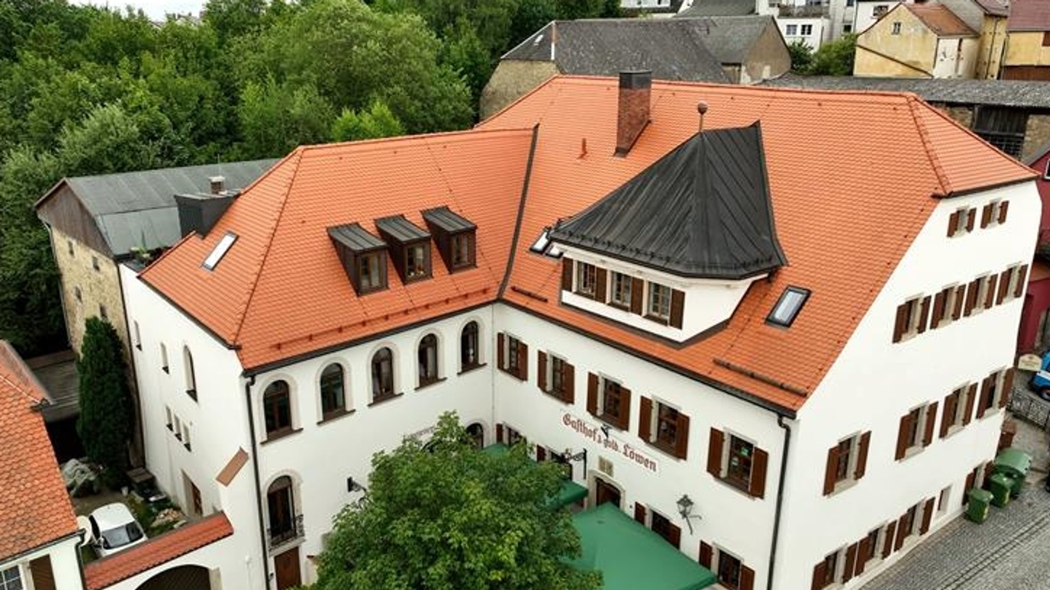 Gasthof zum goldenen Löwen in Marktredwitz - Luftbild von oben mit einem Baum vorm Wirtshaus und grünen Sonnenschirmen.