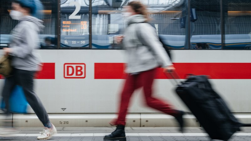 Zwei Frauen laufen auf einem Bahnsteig. Im Hintergrund ist ein Zug der Deutschen Bahn zu sehen. 