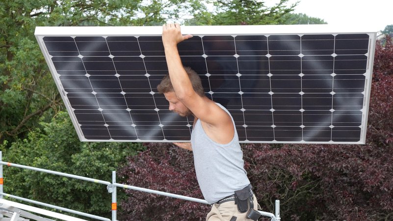 Handwerker montiert Solarmodul auf Hausdach | Bild: picture alliance / Caro | Hoffmann Handwerker montiert Solarmodul auf Hausdach