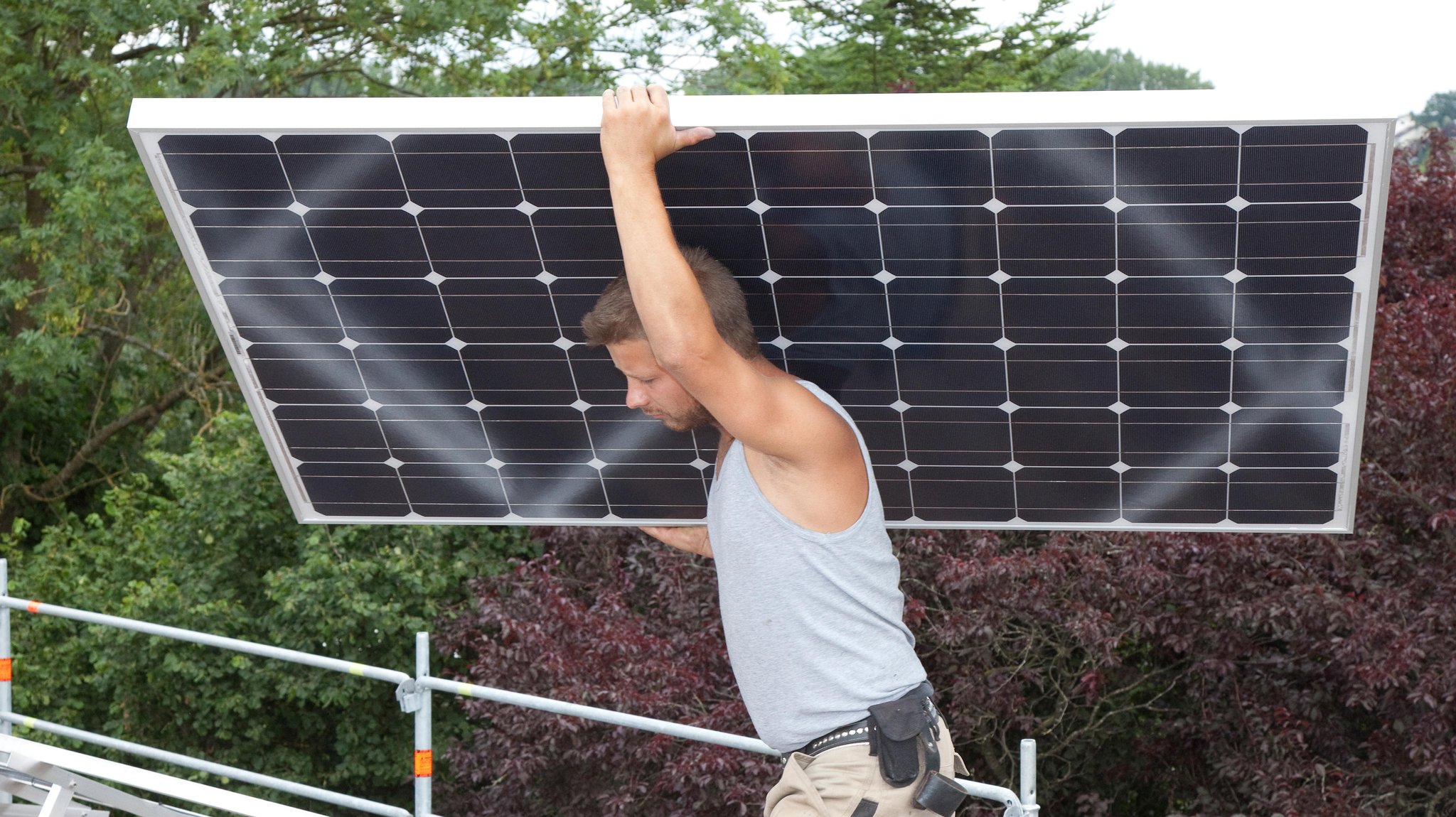 Handwerker montiert Solarmodul auf Hausdach