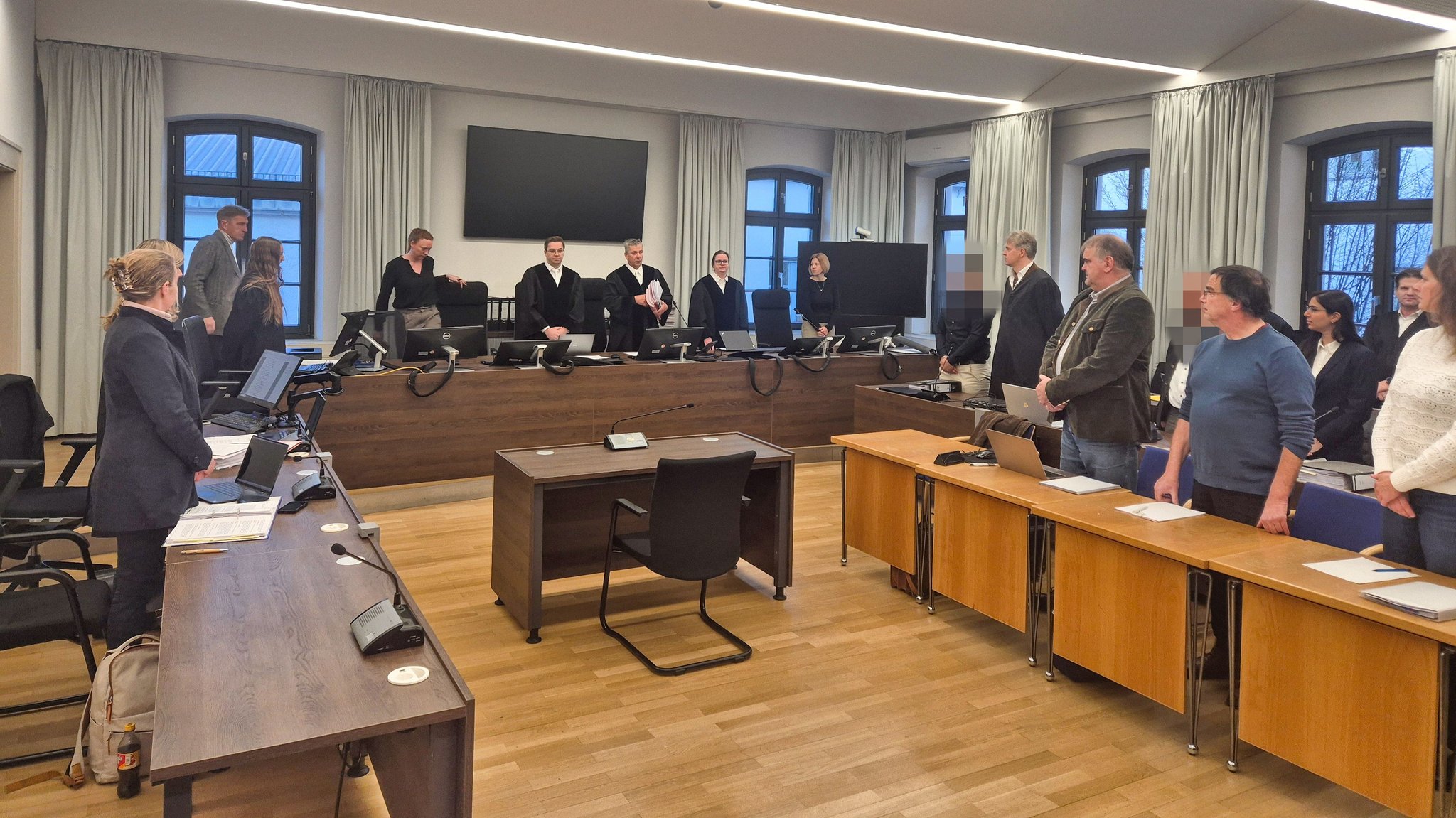 Ein Gerichtssaal des Memminger Landgerichts, die Angeklagten rechts im Hintergrund sind gepixelt, die Personen davor sind Sachverständige.