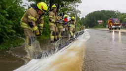 Feuerwehrleute arbeiten an einer von der Günz überfluteten Straße in Ichenhausen, um das Wasser aus der Stadt fernzuhalten. | Bild:picture alliance/dpa | Stefan Puchner