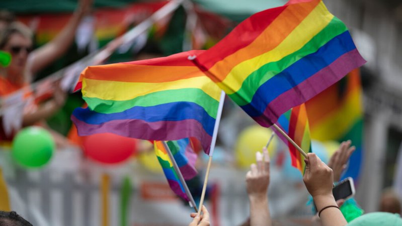(Symbolbild) Menschen wehen Regenbogen-Flaggen bei einer Parade. | Bild: stock.adobe.com (Symbolbild) Menschen wehen Regenbogen-Flaggen bei einer Parade.