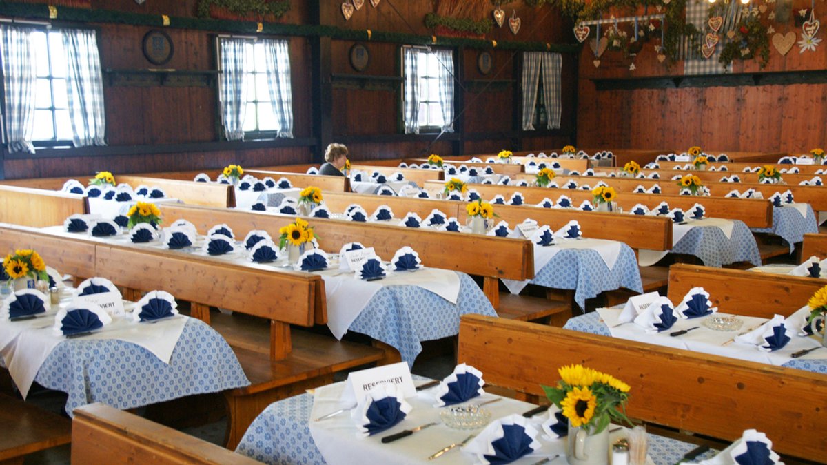 In einem Wiesnzelt sind viele dekorierte Tische zu sehen - die alle reserviert sind | Bild: BR/ Natasha Heuse In einem Wiesnzelt sind viele dekorierte Tische zu sehen - die alle reserviert sind