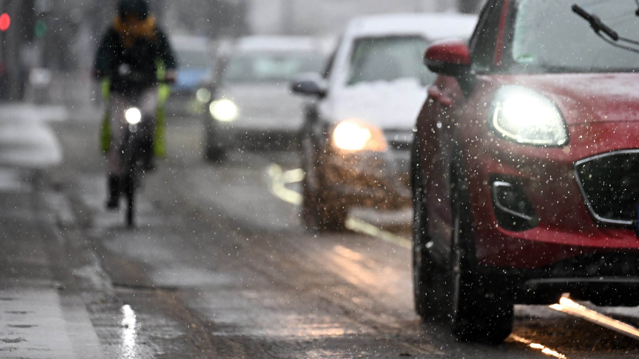 Radler und Autos im Schneeregen