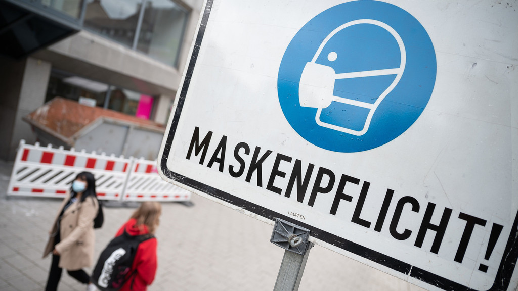 Ein Schild in einer Fußgängerzone macht auf die Maskenpflicht aufmerksam. 