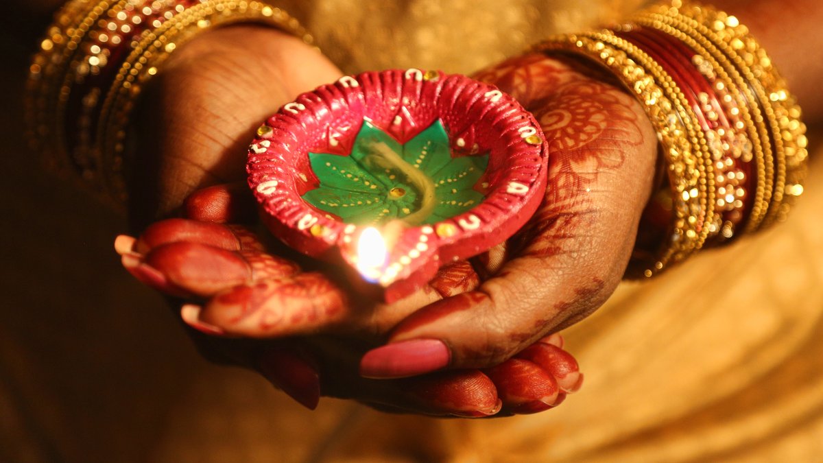 Eine Hindu hält eine kleine Tonlampe beim Diwali-Fest in der Hand.