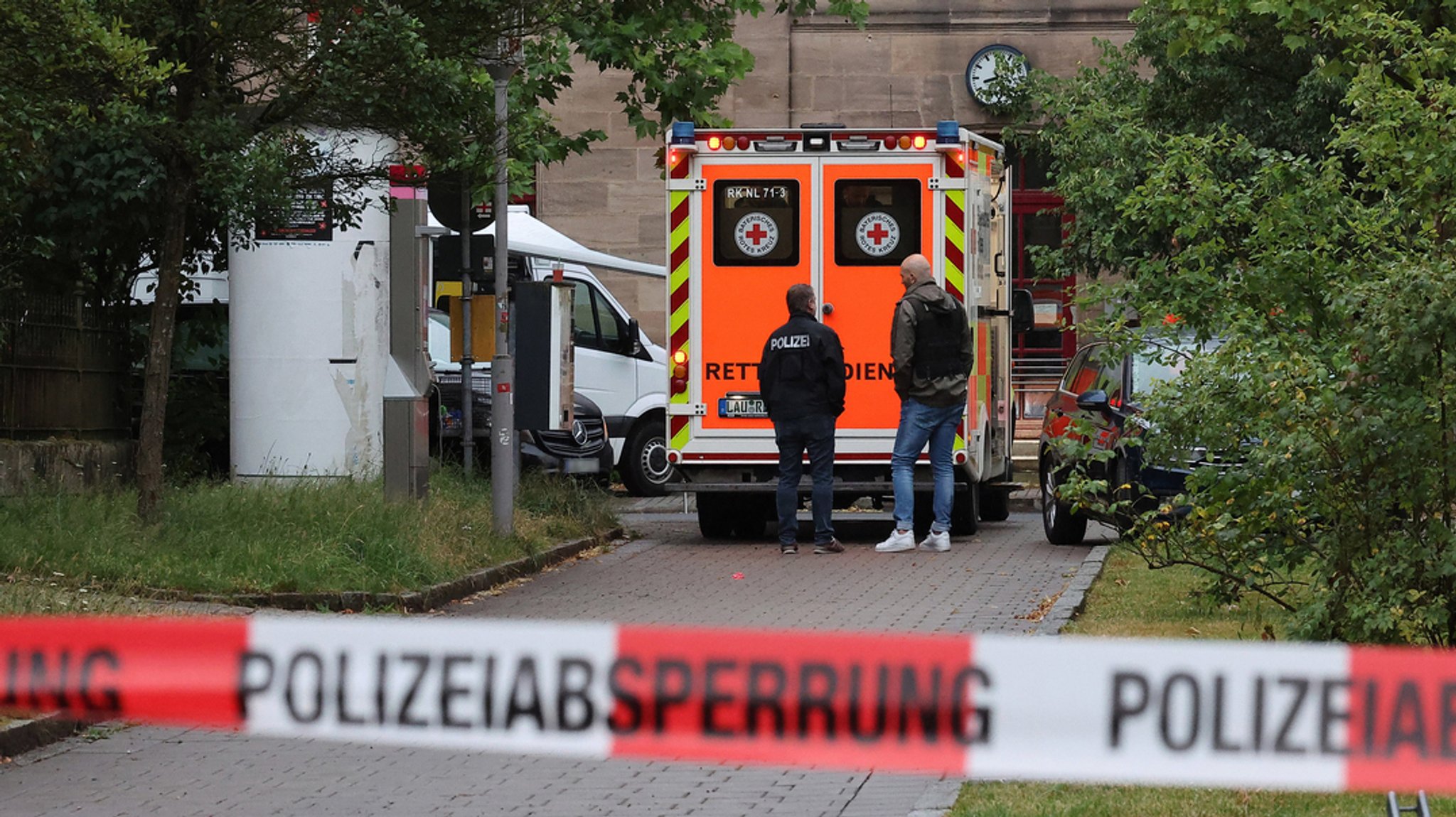 An einem S-Bahnhof in Lauf an der Pegnitz steht hinter rot-weißem Polizeiabsperrband ein Einsatzwagen des Rettungsdienstes. Hier hat die Polizei einen Mann erschossen, der die Beamten mit einem Messer angegriffen hat.