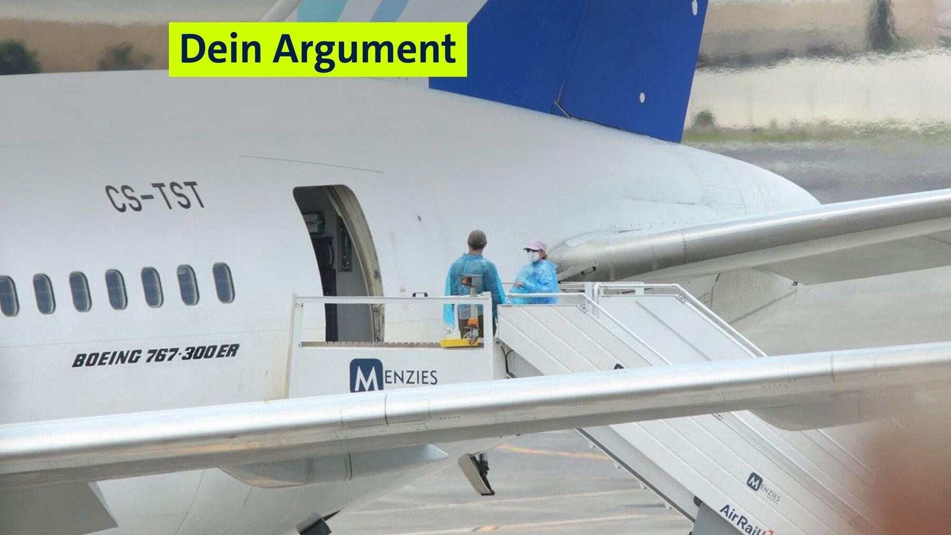 Menschen mit Schutzkleidung stehen an einem Flugzeug. 