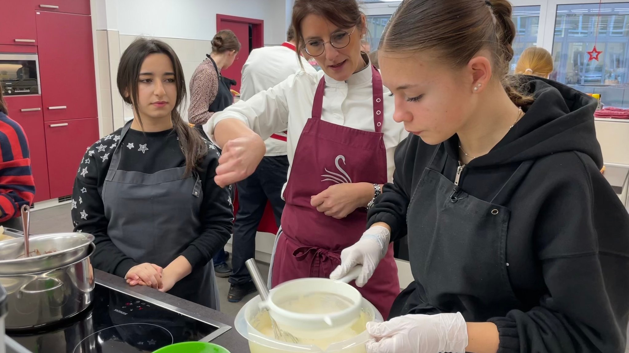 Köchin Eva-Maria Heeg leitet Schülerin Sarah Zimmermann beim Zubereiten der Nachspeise an.