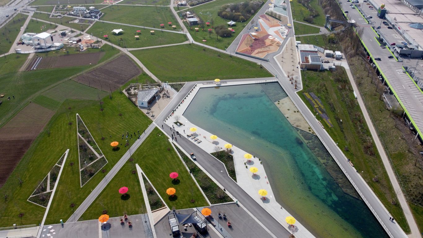 Luftaufnahme des Landesgartenschau-Geländes mit Blick auf den künstlichen See, Wiesen und den Spielplatz mit Tartanbelag.